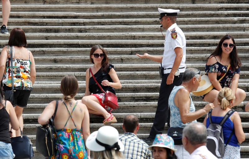 A municipal policeman asks a tourist to rise from Rome's Spanish Steps