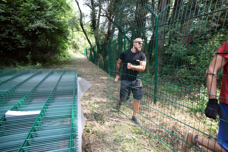 Workers installs a fence on the bank of the Kolpa river in Preloka