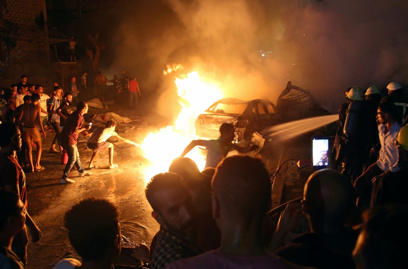 People extinguish a fire from a blast outside the National Cancer Institute, Cairo