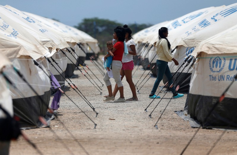 Venezuelan migrant women walk through a camp run by the UN refugee agency UNHCR in Maicao