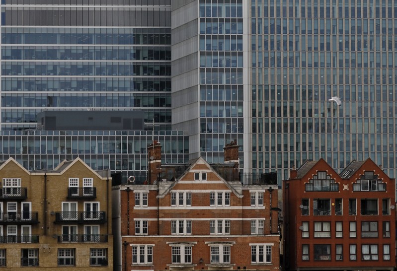 Apartment buildings are backdropped by skyscrapers of banks at Canary Wharf in London