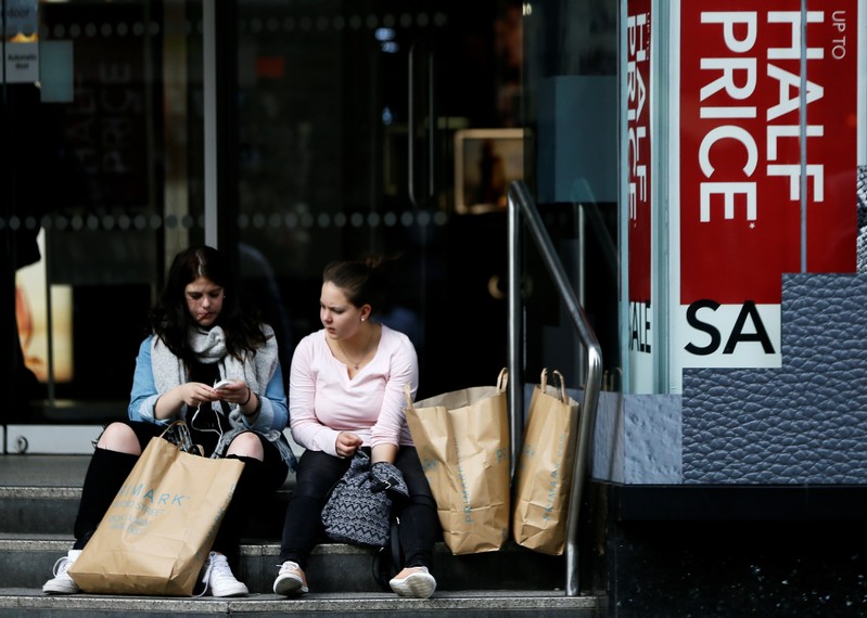 Two shoppers sit with their bags on Oxford Street in London