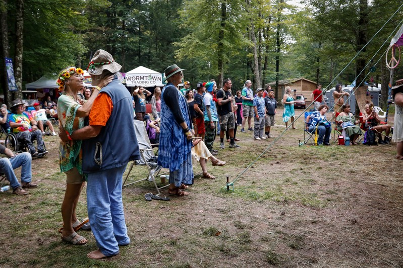 People listen to a band during a celebration of the 50th anniversary of the Woodstock Festival on Max Yasgur's original homestead in Bethel, New York