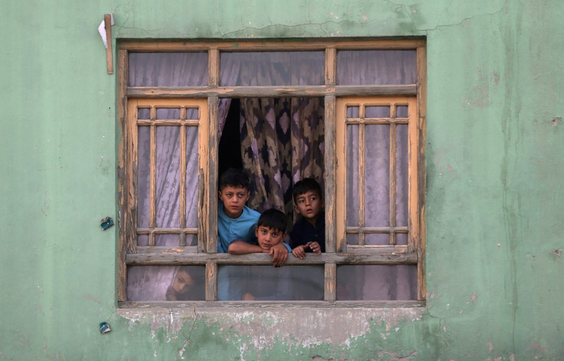 FILE PHOTO: Afghan children look out from a broken window at the site of a blast in Kabul