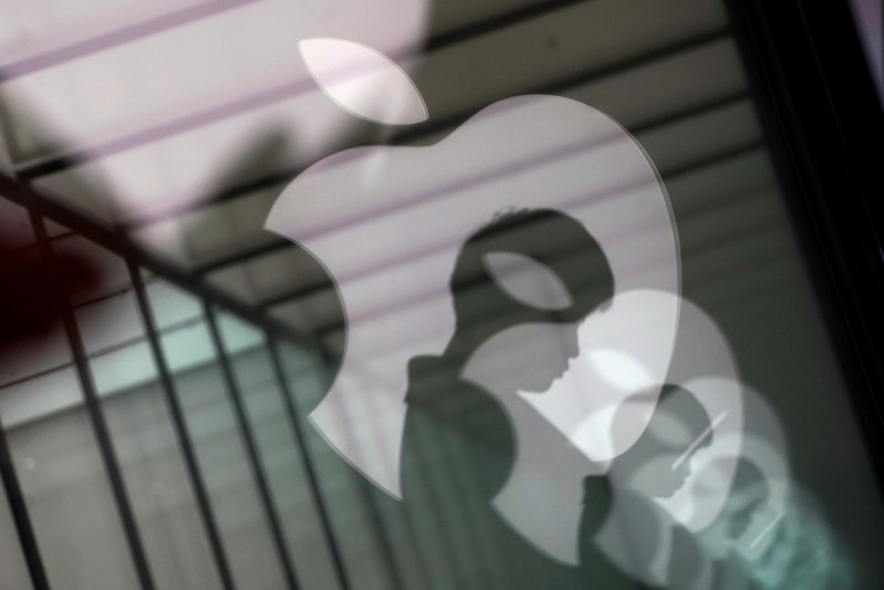 FILE PHOTO: Apple company logos are reflected on the glass window outside an Apple store in Shanghai