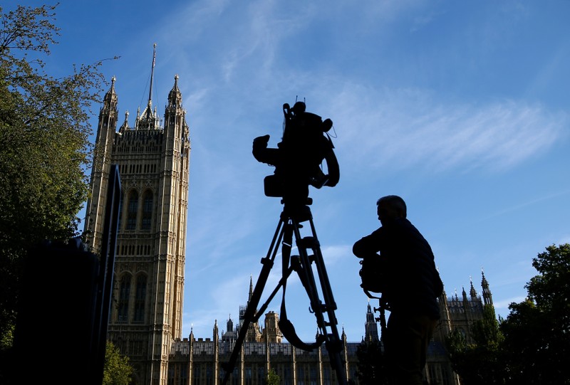 A member of the media sets up a TV camera in front of the Houses of the Parliament in London