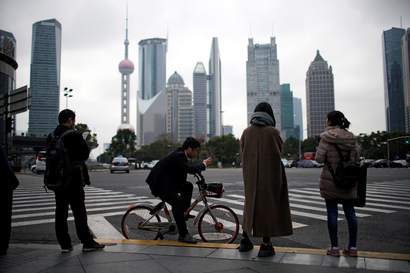 People stand on the sidewalk at Lujiazui financial district in Pudong, Shanghai
