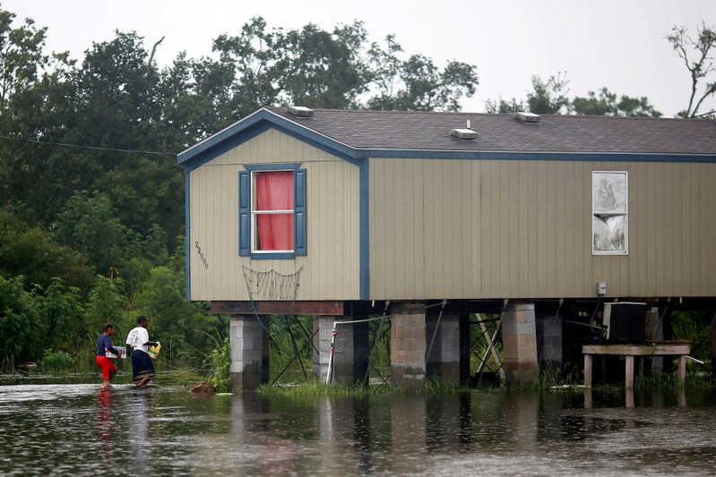 FILE PHOTO: Residents walk through flood water back to their raised house during Hurricane Barry in Plaquemines Parish