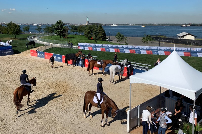 Riders warm up their horses in the practice ring at the Longines Global Champions Tour New York