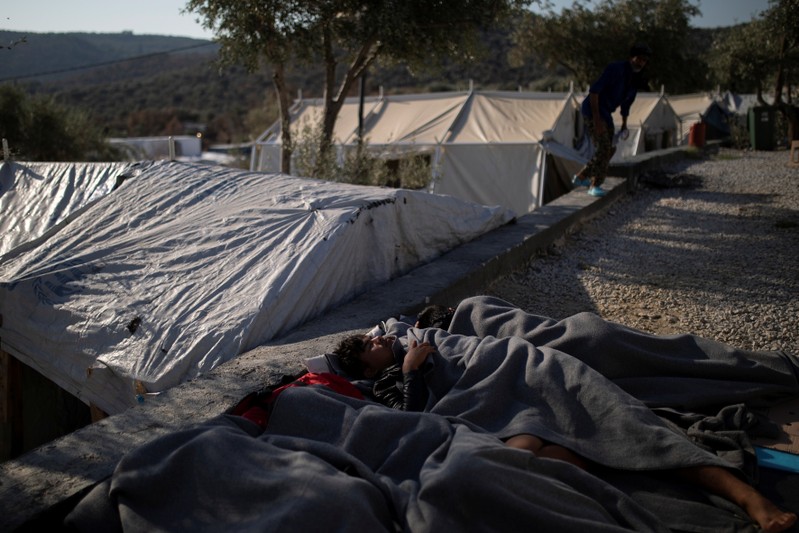 Migrants sleep at a makeshift camp for refugees and migrants next to the Moria camp on the island of Lesbos