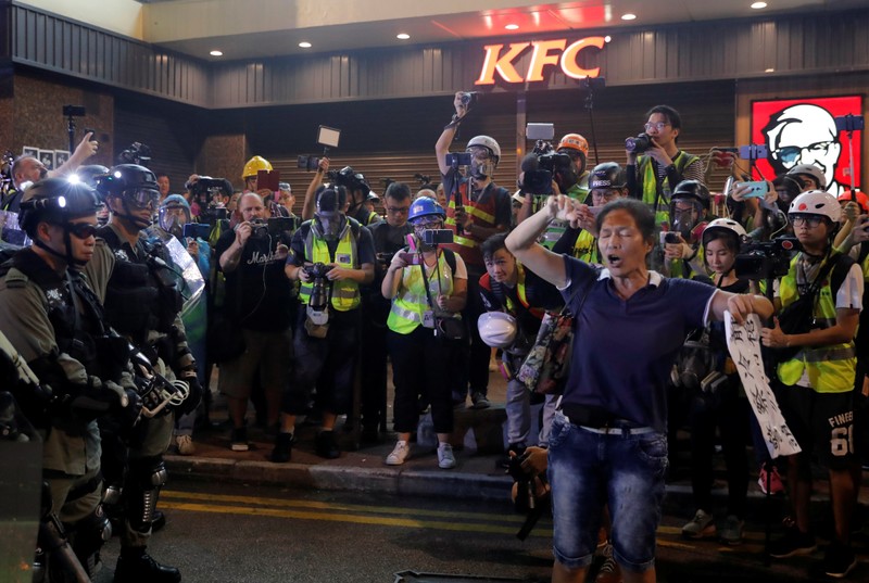 An anti-government protester shouts slogans in front of riot police in Hong Kong