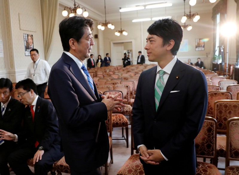 FILE PHOTO: Japan's Prime Minister Shinzo Abe talks with his party's lawmaker Shinjiro Koizumi at the party lawmakers' meeting after the dissolution of the lower house was announced at the Parliament in Tokyo