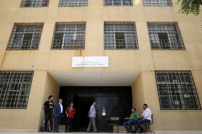 FILE PHOTO - Teachers gather outside one of the public schools during the first day of public school teachers' open strike in Amman