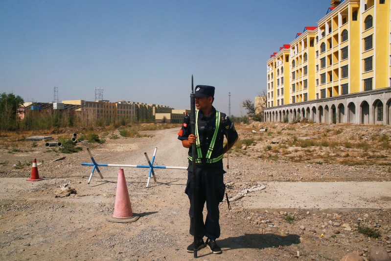 FILE PHOTO - A Chinese police officer takes his position by the road near what is officially called a vocational education centre in Yining