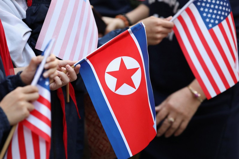 Bystanders holding North Korea and U.S. flags wait for the motorcade of U.S. President Donald Trump in Hanoi