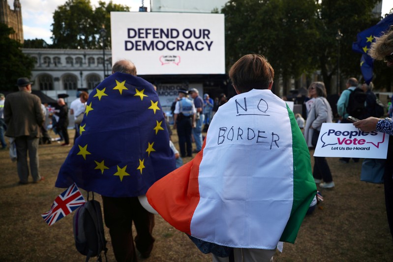FILE PHOTO: A woman wearing an Irish flag and a man wearing an EU flag demonstrate in front of the parliament at Westminster, in London