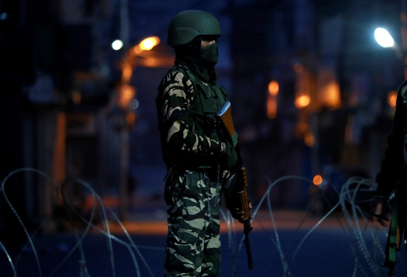 An Indian security force personnel stands guard in a street early morning during restrictions, in Srinagar