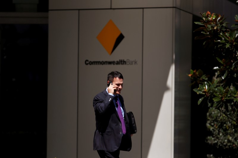 A man uses his mobile phone as he leaves the Commonwealth Bank of Australia building in central Sydney