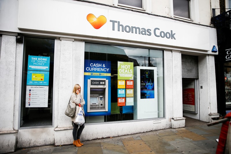 A woman stands on the phone outside of a closed Thomas Cook store in London