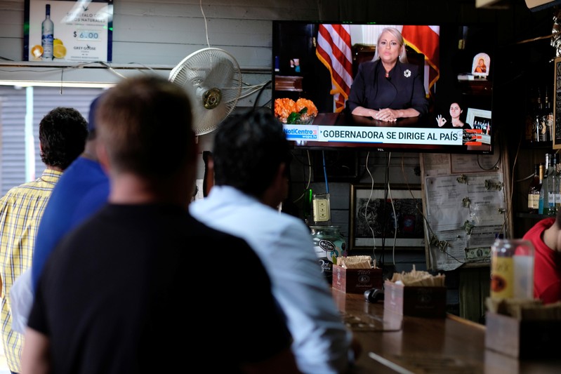 People watch television at a bar as Puerto Rico's Governor Wanda Vazquez Garced makes an address regarding the debt restructuring proposal filed in court by an oversight board, in San Juan