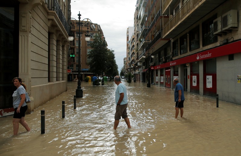 People wade through a flooded street after torrential rains in Orihuela