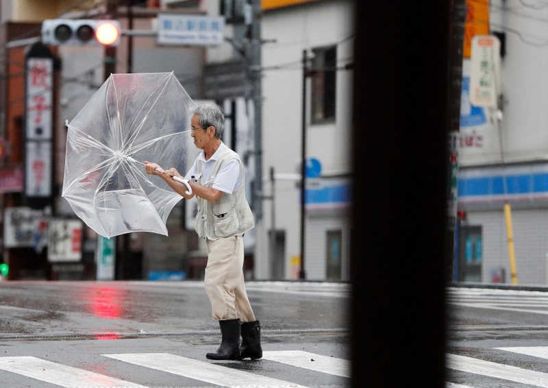 A man using an umbrella struggles against heavy rain and wind wind caused by Typhoon Faxai in Tokyo