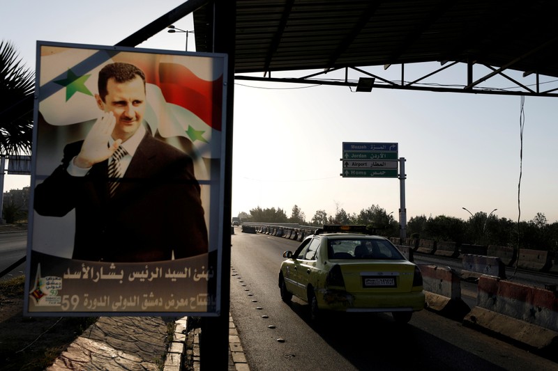 FILE PHOTO: A poster of Syrian President Bashar al-Assad is seen on the main road to the airport in Damascus