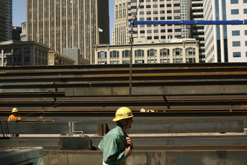 FILE PHOTO: Workers guide steel beams into place at a construction site in San Francisco