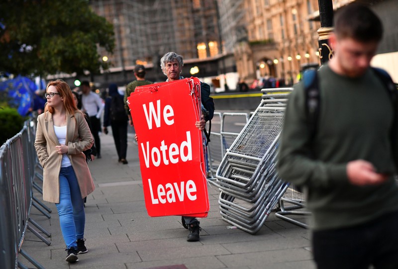 Pro-Brexit protester carries signs outside the Houses of Parliament in London
