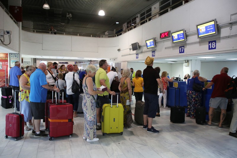 FILE PHOTO: Passengers line up in front of Thomas Cook counters at the airport of Heraklion, on the island of Crete