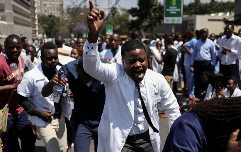Doctors sing and hold placards during a protest over the disappearance of the leader of their union in Harare