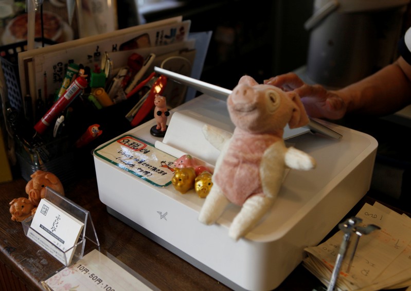 FILE PHOTO: A female staffer types sales data into an iPad-style cash register, with a notice circled in red that reads Ôtax excludedÕ, at Fri-tei restaurant in Tokyo