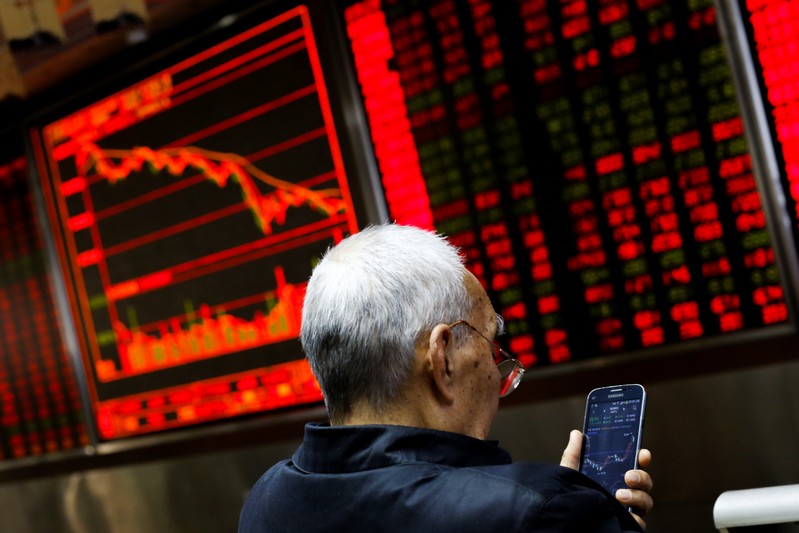 FILE PHOTO: An investor sits in front of a board showing stock information at a brokerage office in Beijing