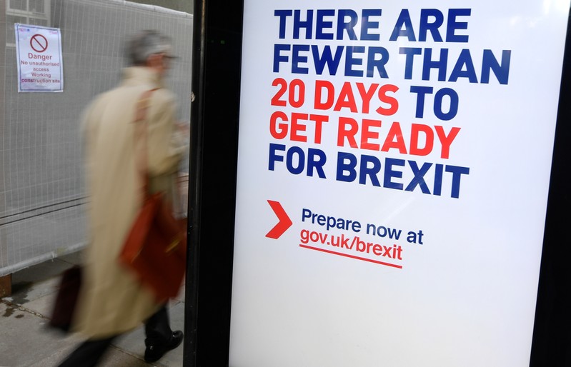 A man walks past an UK government Brexit information campaign poster at a bus stop in central London