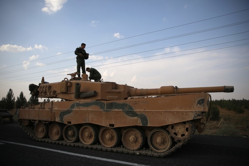 Turkish soldiers stand atop of a tank as army vehicles are moving on a road near the Turkish border town of Ceylanpinar