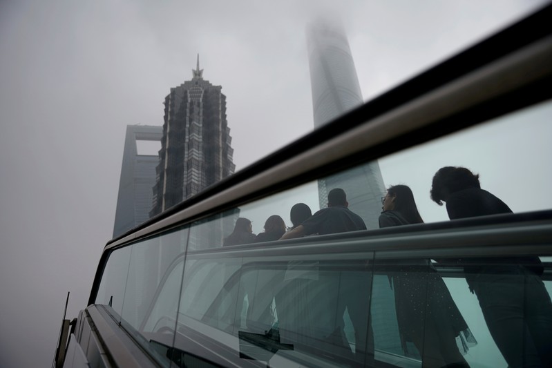 FILE PHOTO: People ride an escalator near skyscrapers at Lujiazui financial district in Shanghai