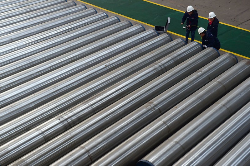 Workers check on seamless steel pipes at a factory of a steel products manufacturer in Cangzhou, Hebei