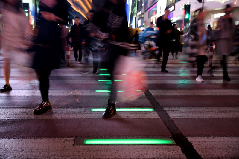 People walk on a crossing with light signals for pedestrians near shopping malls in Shenyang