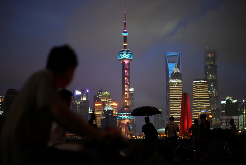 People visit on a bridge in front of the financial district of Pudong in Shanghai