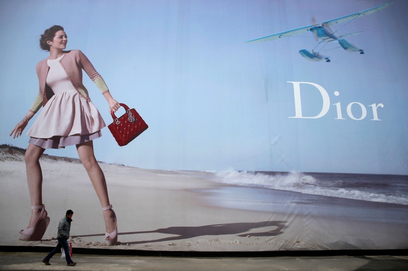 FILE PHOTO: A man walks past a Dior advertisement outside a shopping mall in Wuhan