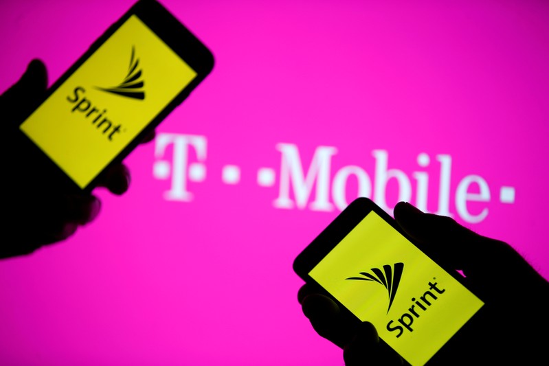 A smartphones with Sprint logo are seen in front of a screen projection of T-mobile logo, in this picture illustration