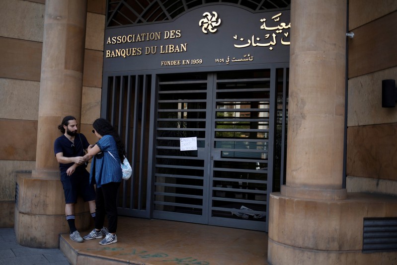 A couple stands outside the closed entrance of the Association of Banks in Lebanon in downtown Beirut