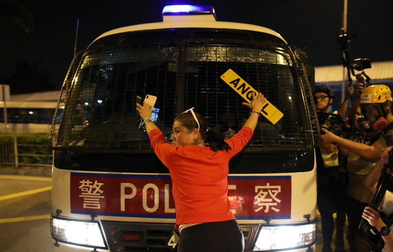 FILE PHOTO: An anti-government demonstrator stands in fron of a police vehicle during a protest against the invocation of the emergency laws in Hong Kong