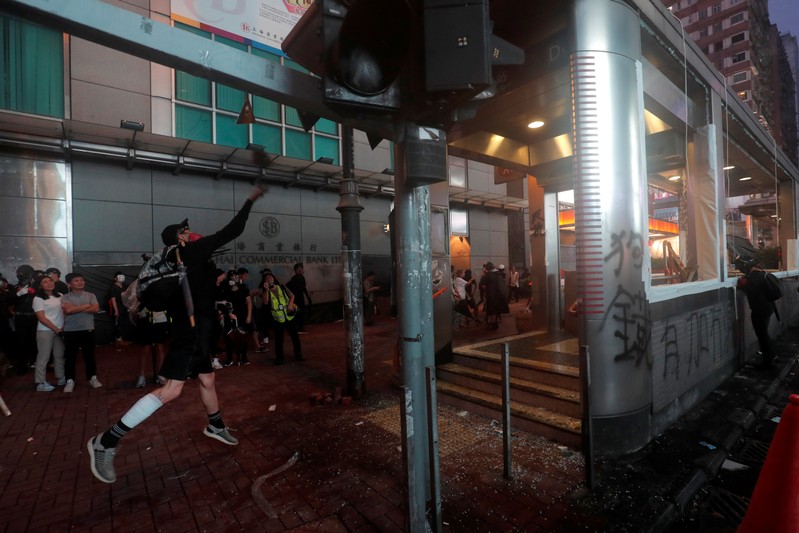 An anti-government protester throws a rock to the entrance of a metro station, in Hong Kong