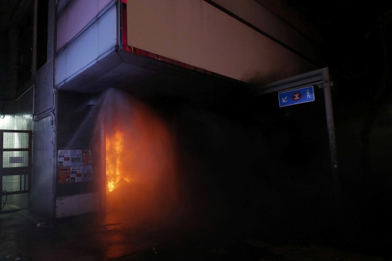 Fire extinguisers try to put out a fire set by anti-government protesters in one of the metro entrances in Causeway Bay district in Hong Kong