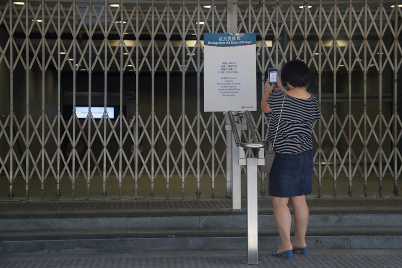 FILE PHOTO: A woman takes a picture of an information board at the suspended metro station in Tsim Sha Tsui district, in Hong Kong