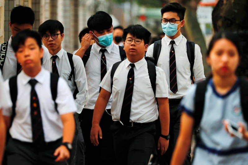Some students from La Salle College wear masks, which have been banned at protests under emergency powers, as they walk to school in Hong Kong