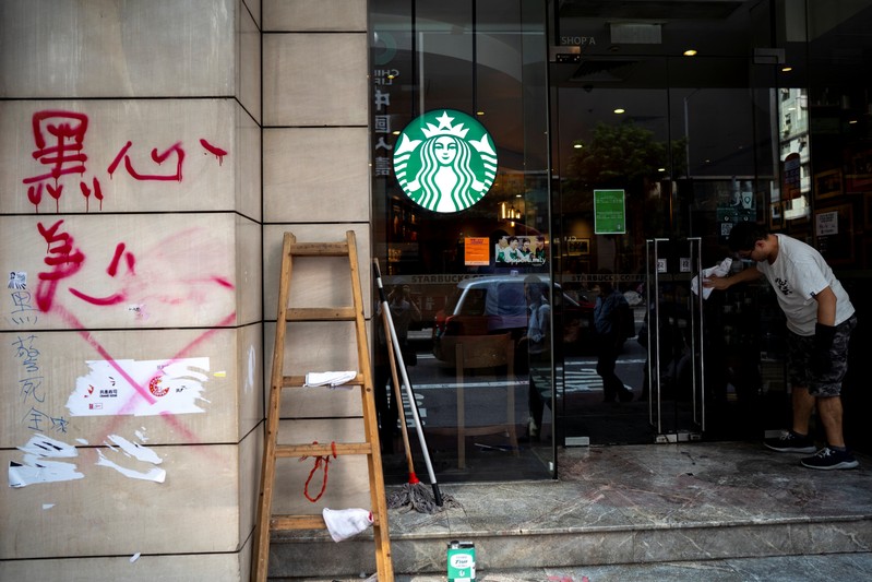 FILE PHOTO: A worker cleans graffiti sprayed by anti-government protesters at a Starbucks coffee shop a day after a protest in Causeway Bay district, Hong Kong