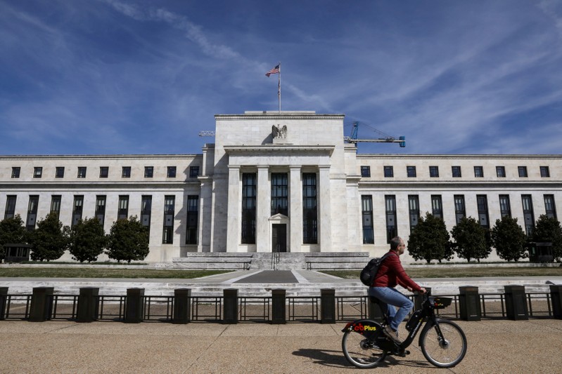 A man rides a bike in front of the Federal Reserve Board building on Constitution Avenue in Washington