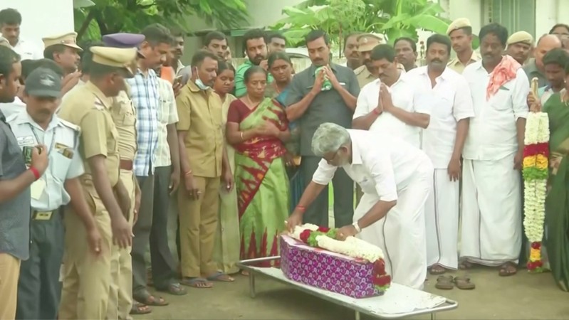 A man places flowers on the coffin of a toddler who died after getting stuck in a borewell, in Trichy